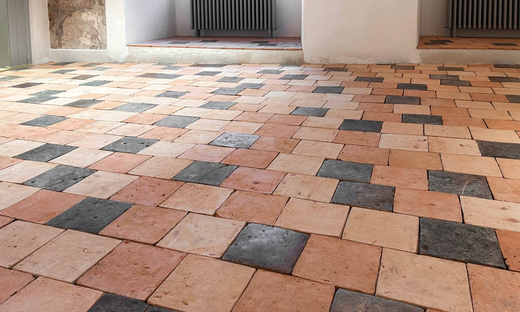 Der Bodenbelag kombiniert wiederverwendete historische Tonplatten mit nachproduzierten Exemplaren und vereint so Bestand und Ergänzung zu einem lebendigen Gesamtbild. (Foto Claudio Oertig) 